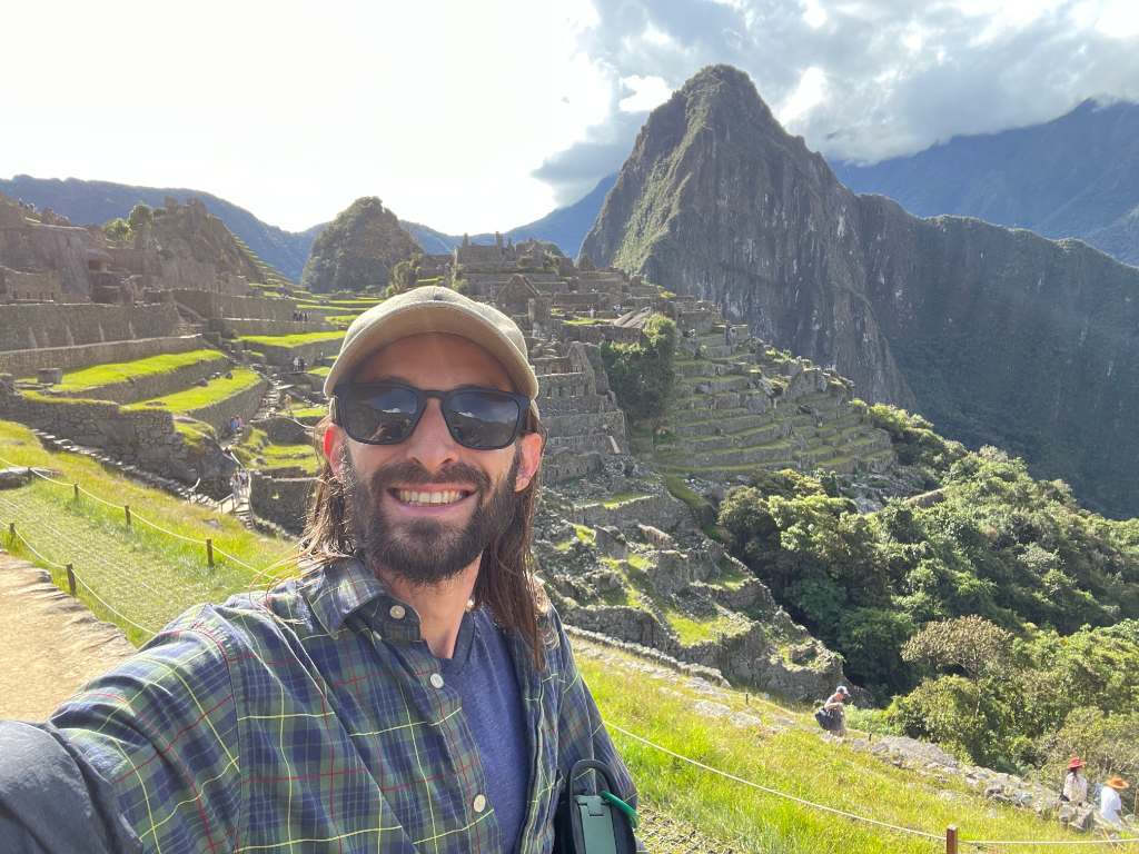 smiling guy with a hat in front of a waterfall